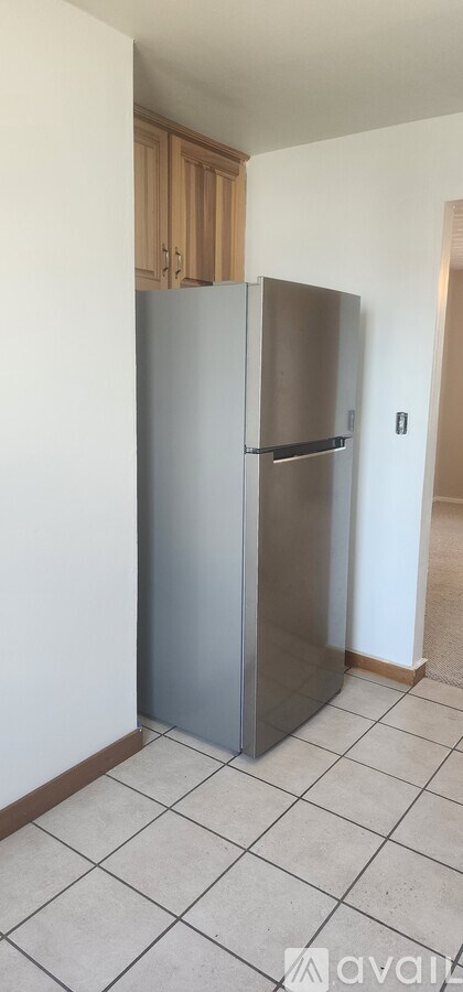 A silver refrigerator in a kitchen with a white tiled floor.