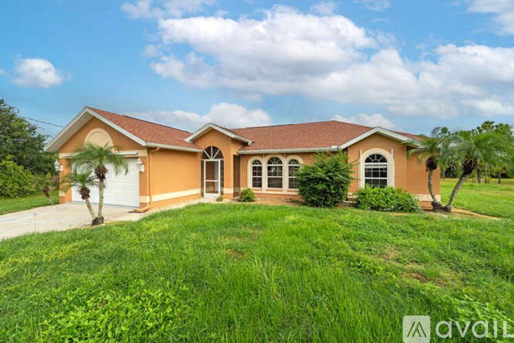 A house with a brown roof and a white garage door is surrounded by green grass.