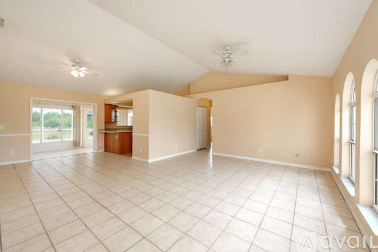 A large empty room with tiled flooring and a ceiling fan.
