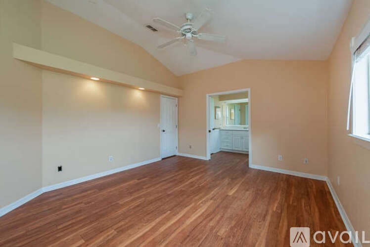 A spacious room with wooden flooring and a ceiling fan.