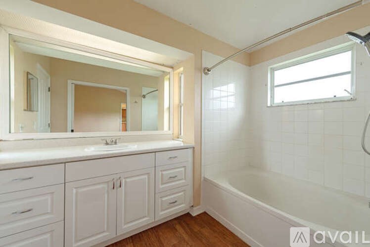 A bathroom with white cabinets and a large mirror.