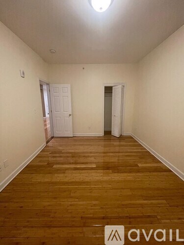 A room with wooden flooring and two doors.