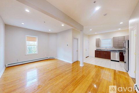 A spacious room with wooden flooring and white walls.