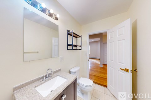 A bathroom with a sink, toilet, and mirror.