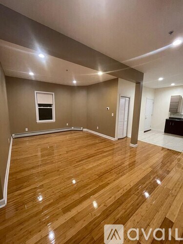 A spacious room with wooden flooring and a window.