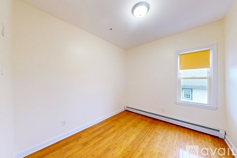 A spacious room with wooden flooring and a white ceiling.