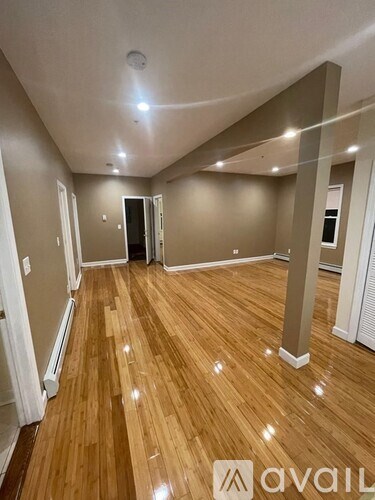 A spacious room with wooden flooring and a high ceiling.