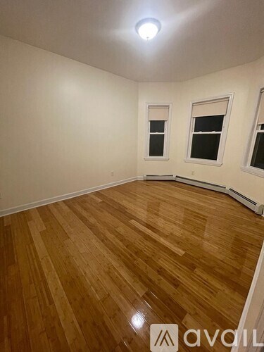 A room with wooden flooring and two windows.