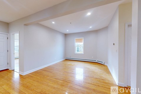 A room with wooden flooring and two windows.