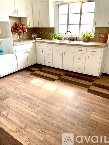 A kitchen with white cabinets and a wooden floor.