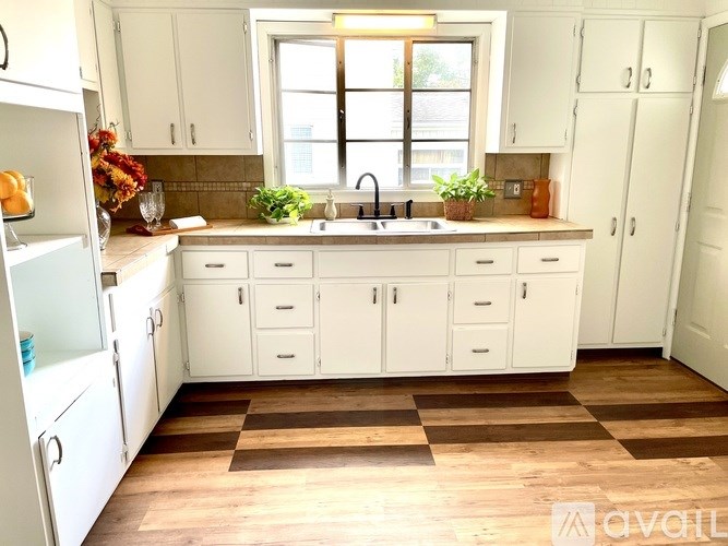 A kitchen with white cabinets and a checkered floor.