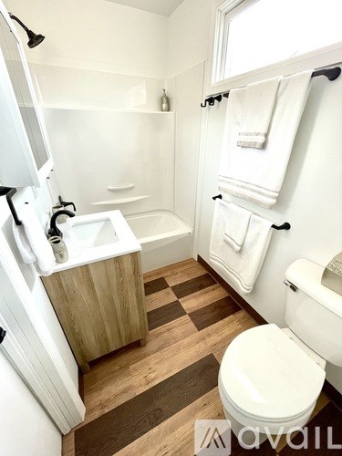A white toilet sits in a bathroom with a wooden sink and a bathtub.