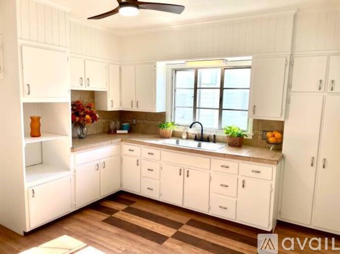 A kitchen with white cabinets and a wooden floor.