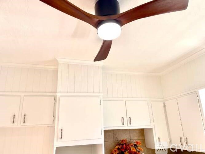 A room with wooden flooring and a staircase in the background.