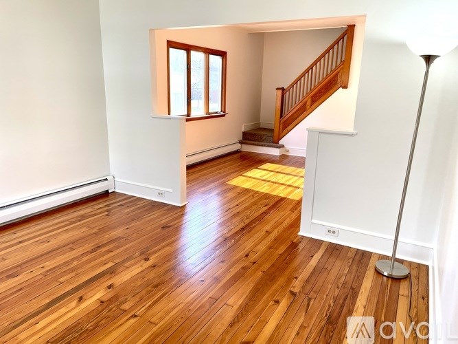 A wooden floor in a room with a window and a staircase.