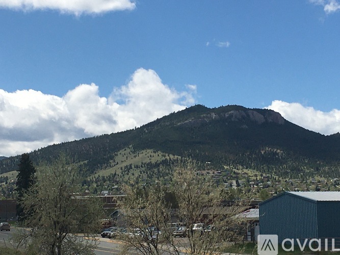 A mountain with a town in the foreground and a building with the word "AVAILABLE" on it.