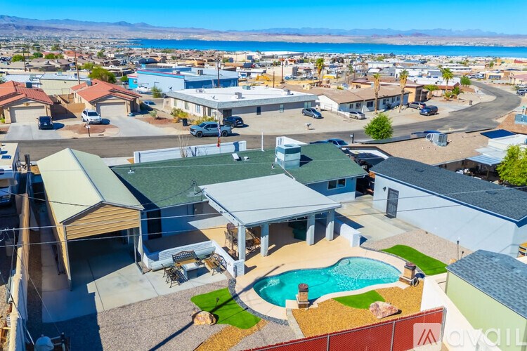 A large house with a pool in the foreground and a residential neighborhood in the background.