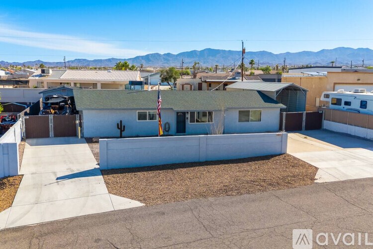 A house with a flag on the front and a mountain range in the background.