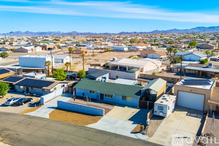 A sunny day in a residential neighborhood with houses and parked cars.