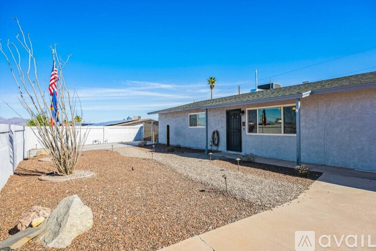 A house with a flag on a stick stands in front of a white fence.