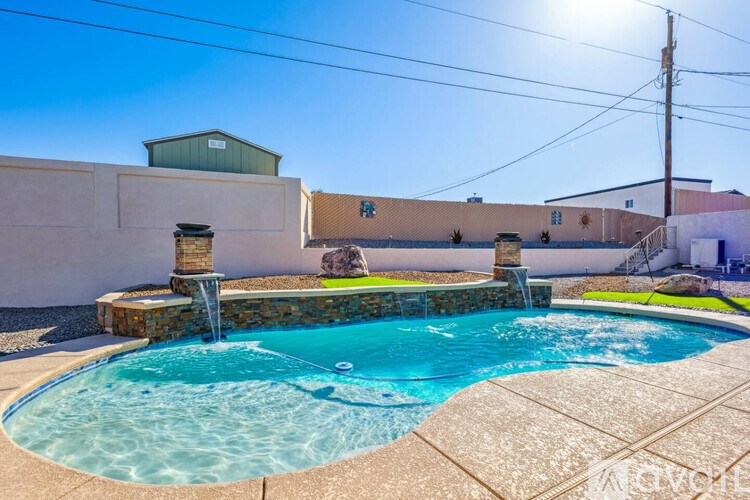 A small pool with a waterfall and a stone wall.