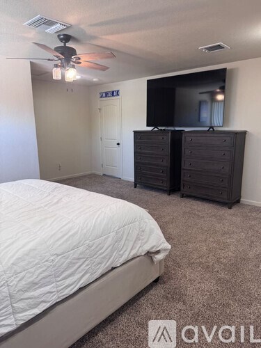 A bedroom with a bed, dresser, and TV.
