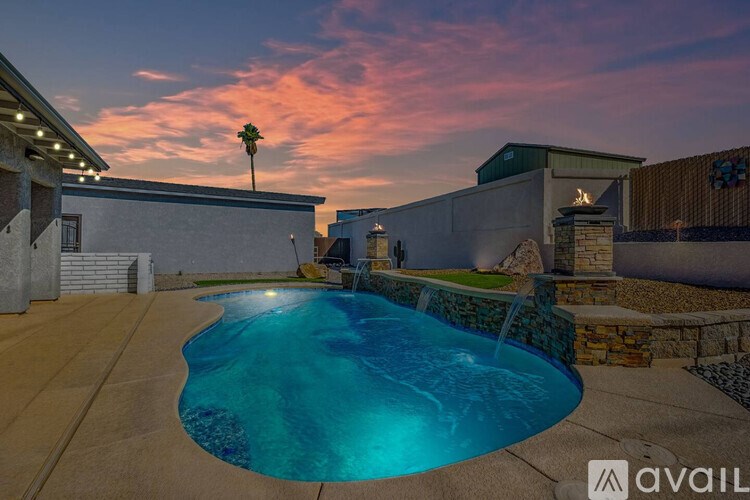 A pool surrounded by a stone wall and a building with a palm tree on top.