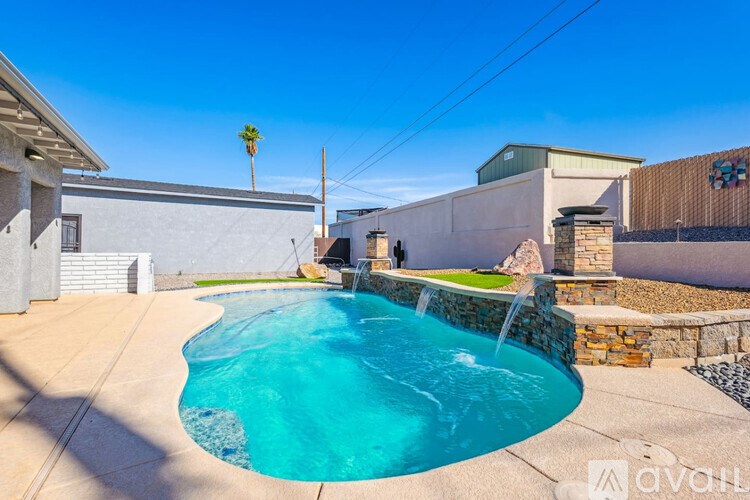 A swimming pool in a backyard with a house and a palm tree in the background.