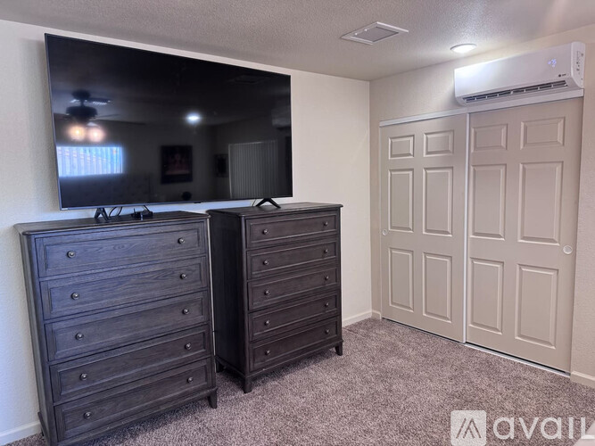 A bedroom with two dressers and a large mirror.