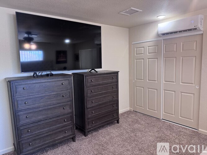 A bedroom with two dressers and a large mirror.