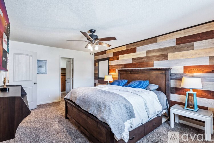 A bedroom with a bed, a ceiling fan, and a wooden accent wall.