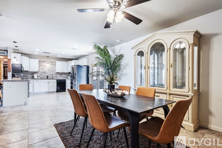 A dining room with a table and chairs and a ceiling fan.