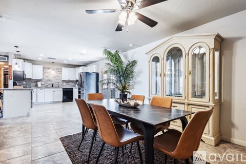 A dining room with a table and chairs and a ceiling fan.
