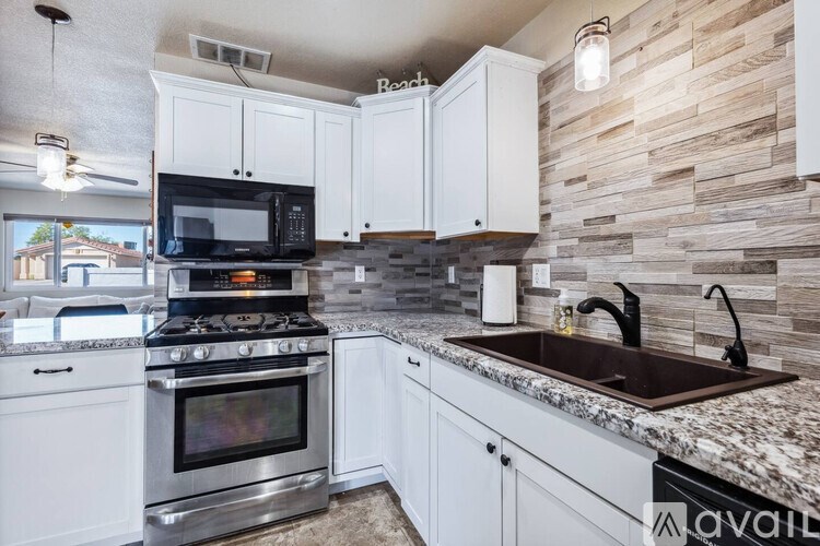 A kitchen with white cabinets and a stone wall backsplash.