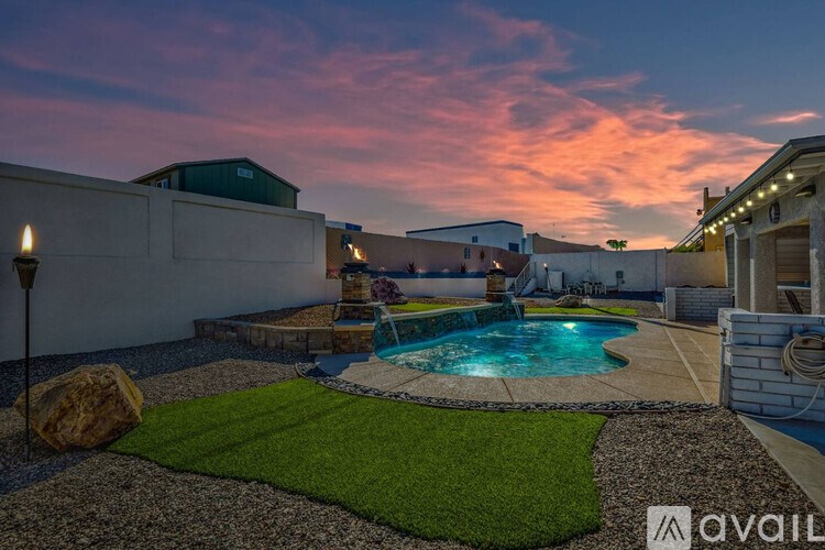 A backyard with a pool and a lit-up patio.