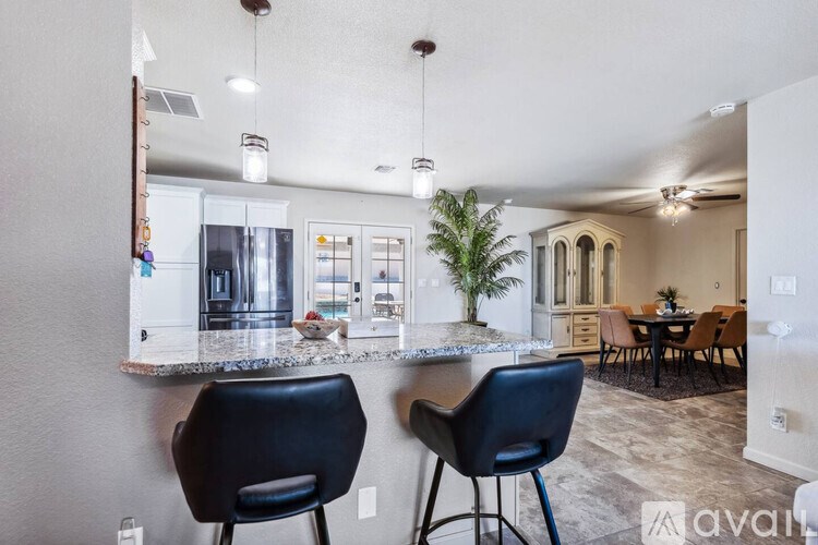A kitchen with a bar area and two black chairs.