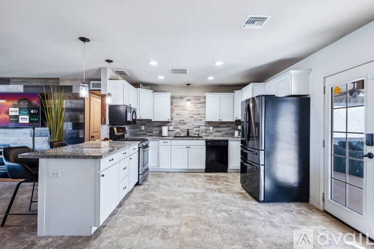 A modern kitchen with a black refrigerator and white cabinets.