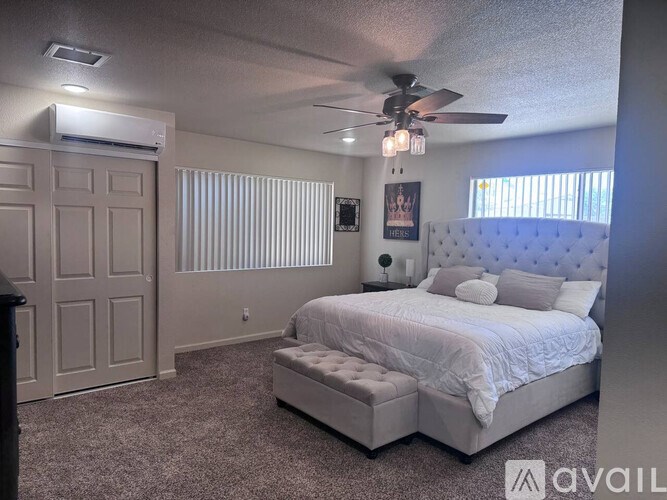 A bedroom with a large bed and a ceiling fan.