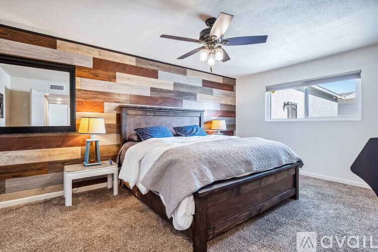 A bedroom with a bed, a bench, and a ceiling fan.