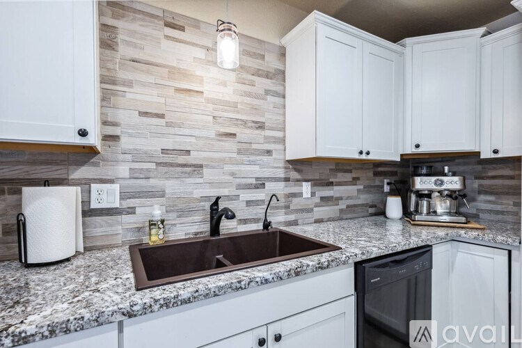 A kitchen with a sink and a wall of tiles.