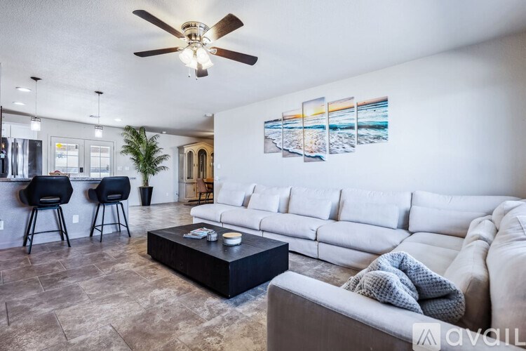 A living room with a white couch, a black coffee table, and a ceiling fan.