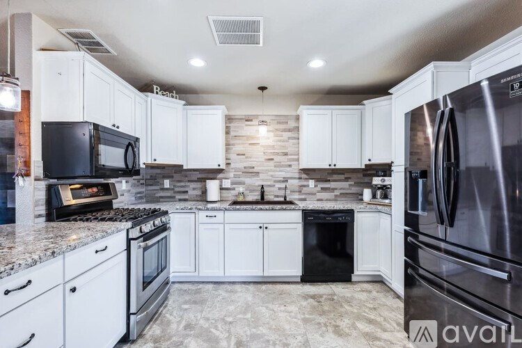 A kitchen with white cabinets and a black refrigerator.