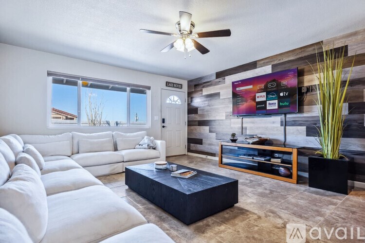 A living room with a white couch and a flat screen TV mounted on the wall.