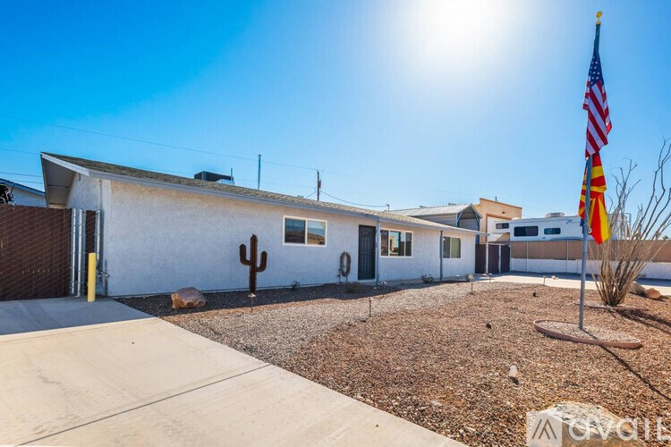 A white house with a cactus in front and an American flag on a pole.