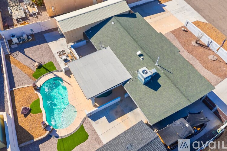 A swimming pool is surrounded by a concrete patio and a green lawn.