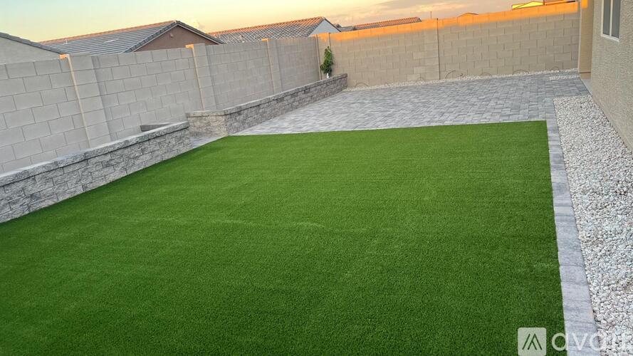 A backyard with a green lawn and a stone wall.