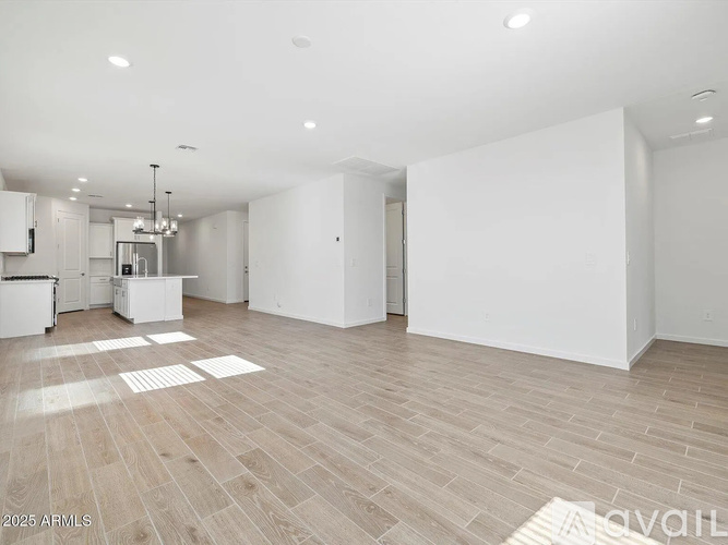 A spacious, empty room with wooden flooring and white walls.