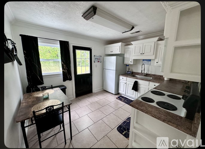 A kitchen with a table and chairs in front of a window.