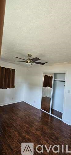 A room with a ceiling fan and wooden flooring.