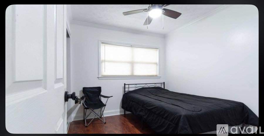 A bedroom with a bed, chair, and window.